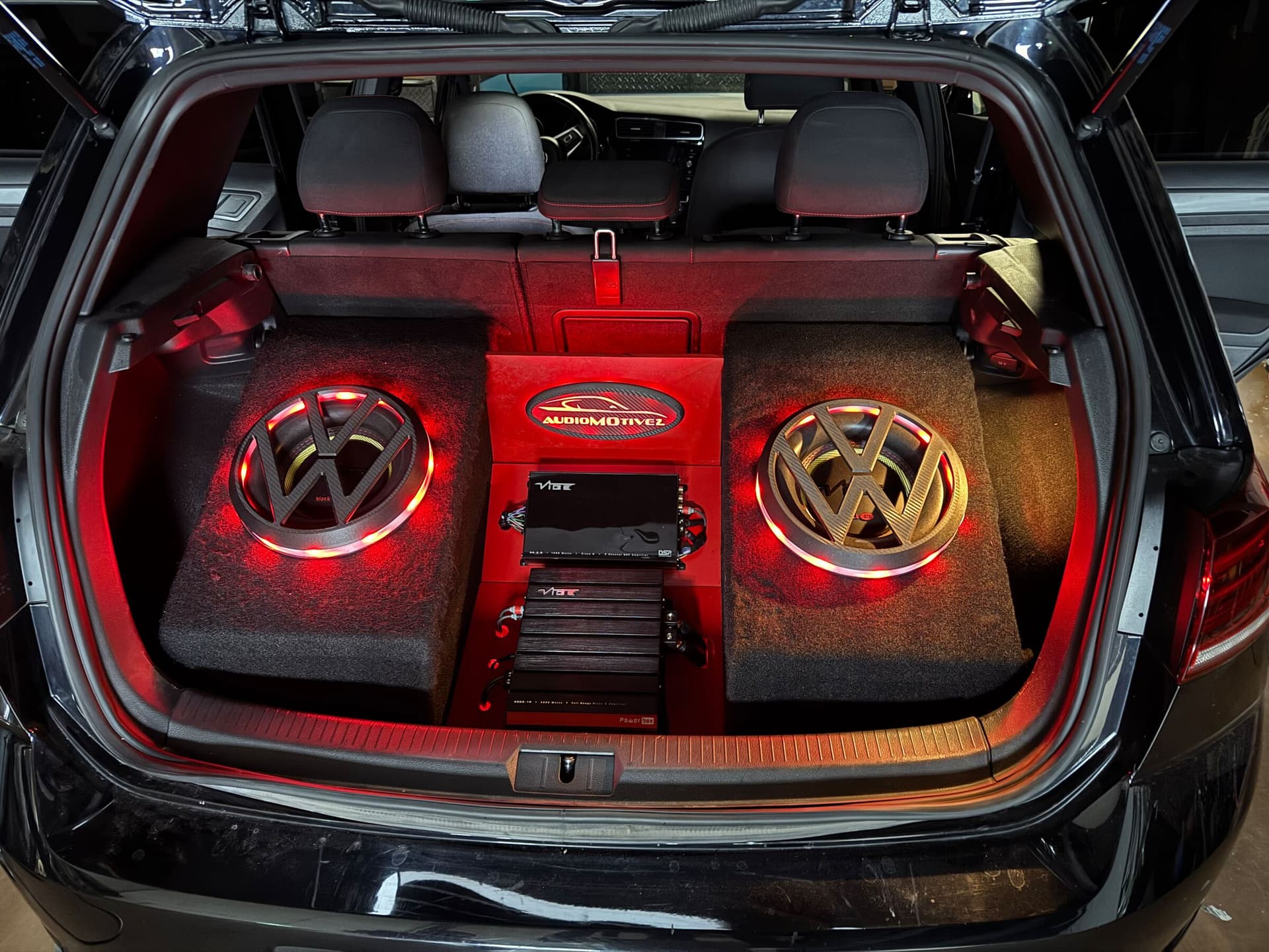 Custom subwoofer and amplifier build in the trunk of a black Volkswagen Golf